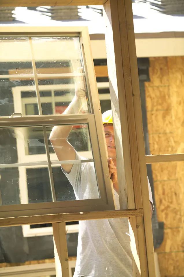 Framing crew member installing a window in a custom home under construction