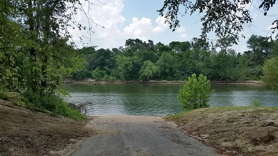 Gravel ramp leading down to the calm, tree-lined Black Warrior River