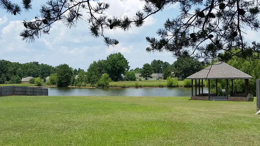 Waterbury's private lake with a shingled pavilion on the bank, framed by pine branches